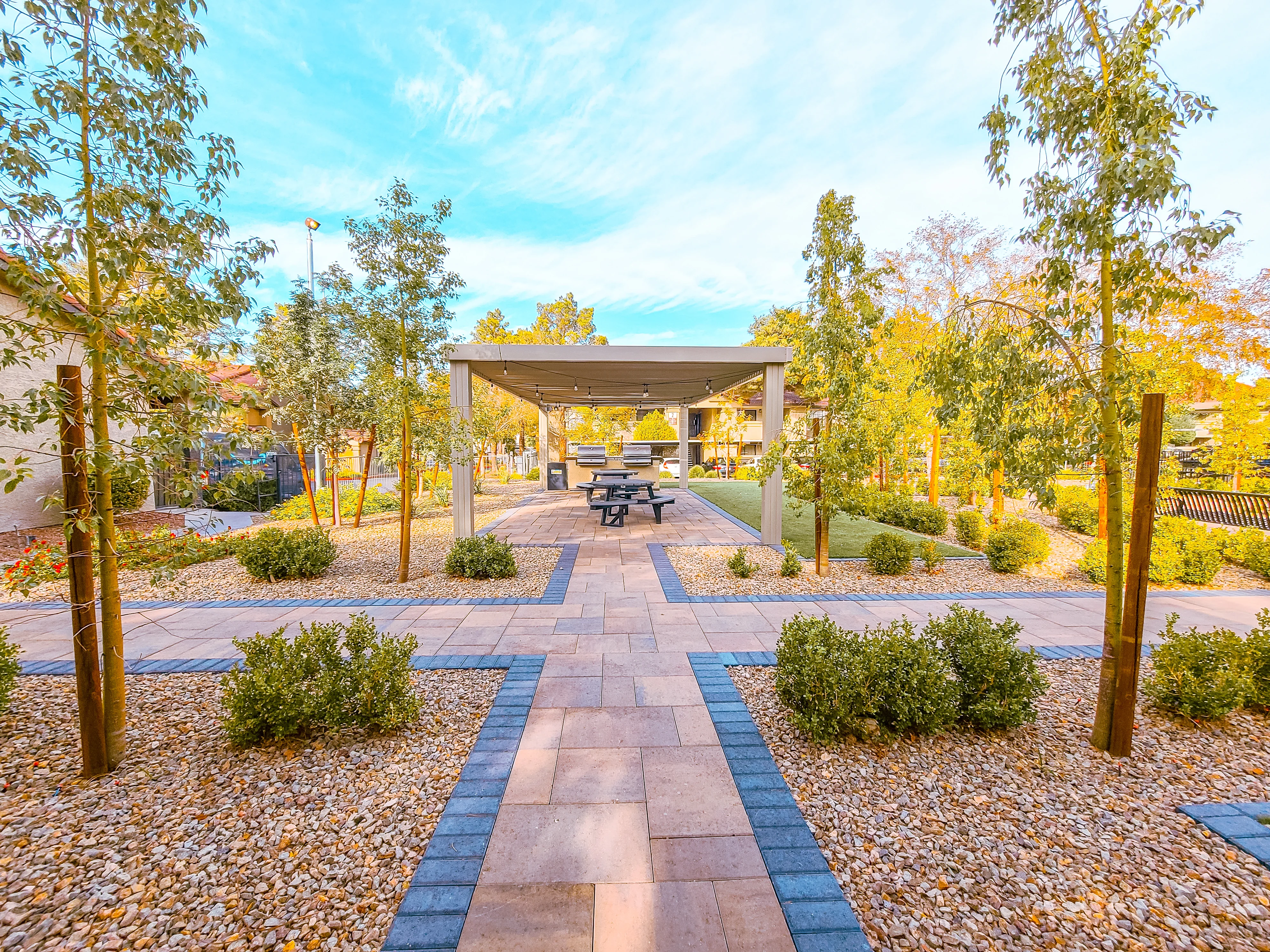 Modern pergola with paver pathways and landscaping in apartment complex courtyard