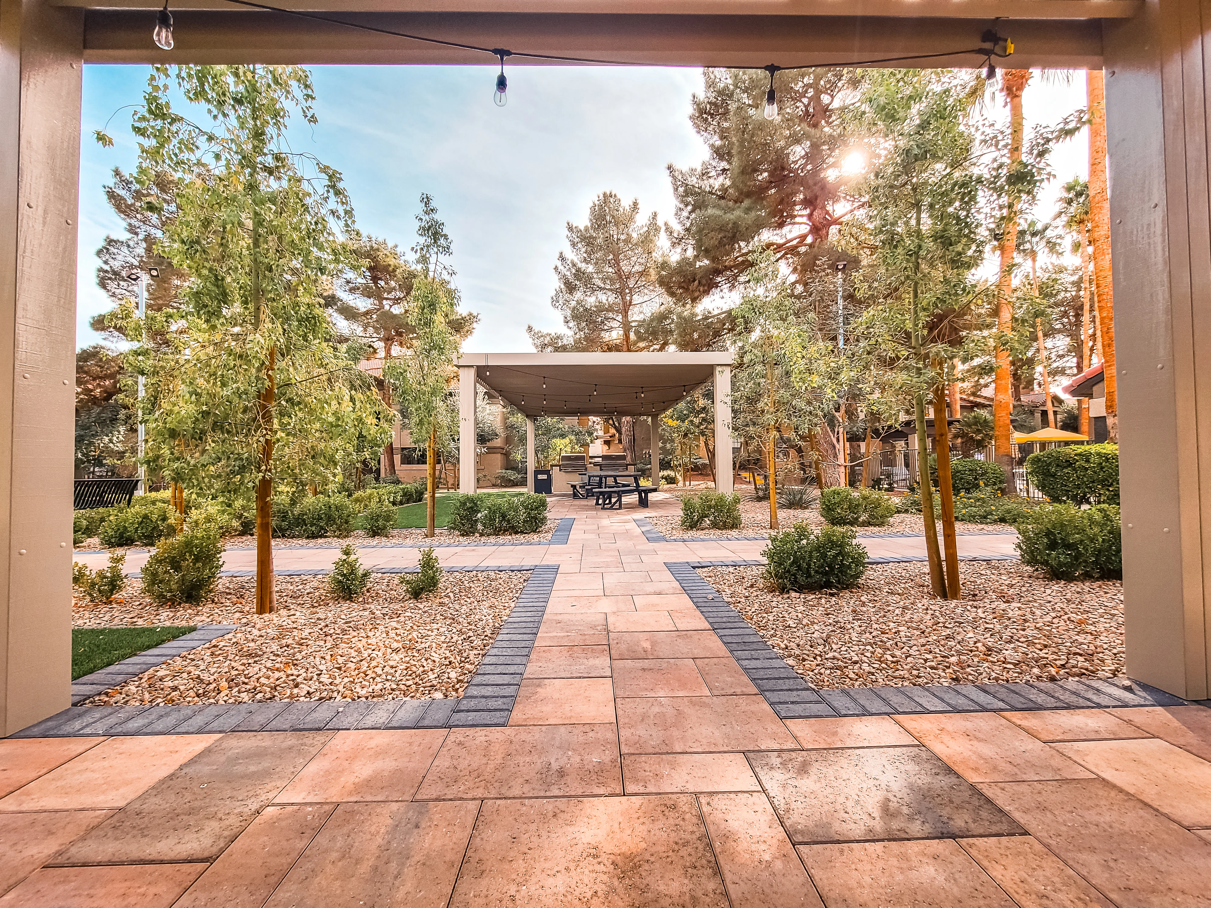Modern patio cover with pergola, stamped concrete walkway, and desert landscaping in courtyard setting